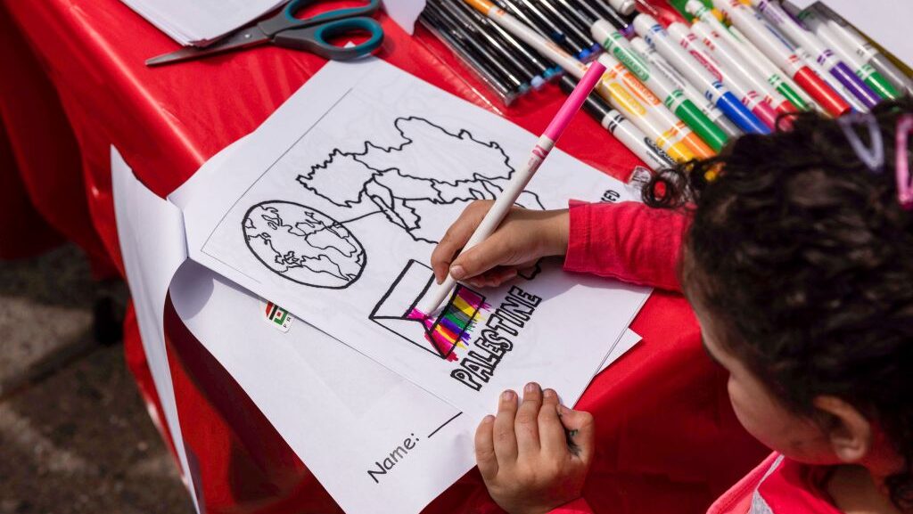 A young girl fills the flag of Palestine with rainbow colors as Palestine rights supporters march to mark the 75th anniversary of Nakba,in Brooklyn, New York,